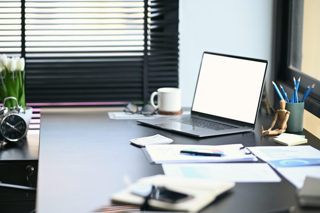Modern office with computer laptop, stationery and financial documents.